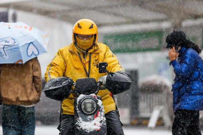 2024年11月14日，在新疆乌鲁木齐市光明路附近，外卖员在风雪中骑行。 新华社记者 王菲 摄